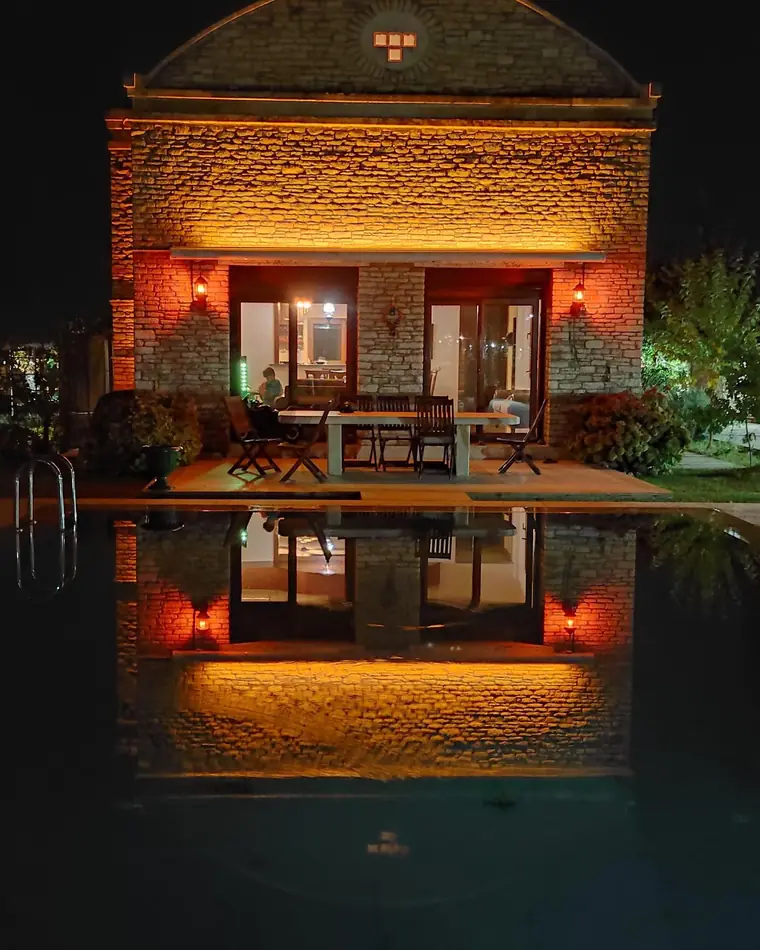Taş evin gece havuza yansıması